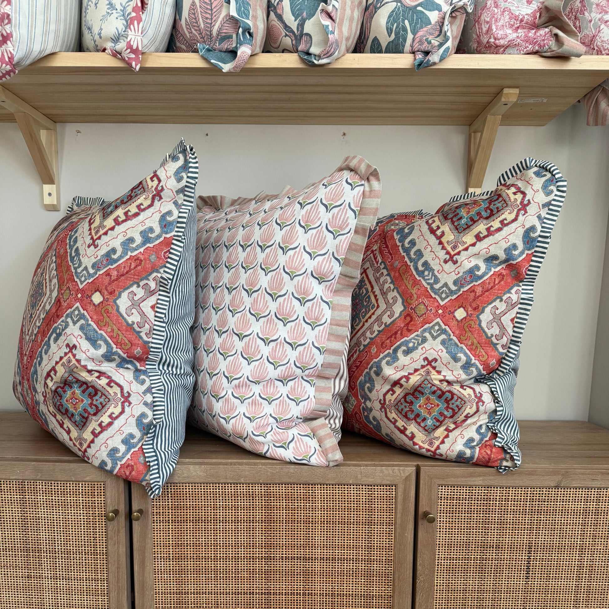 Decorative pillows with geometric patterns on a wooden shelf.
