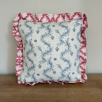 Decorative pillow with floral pattern and pink border on a wooden surface