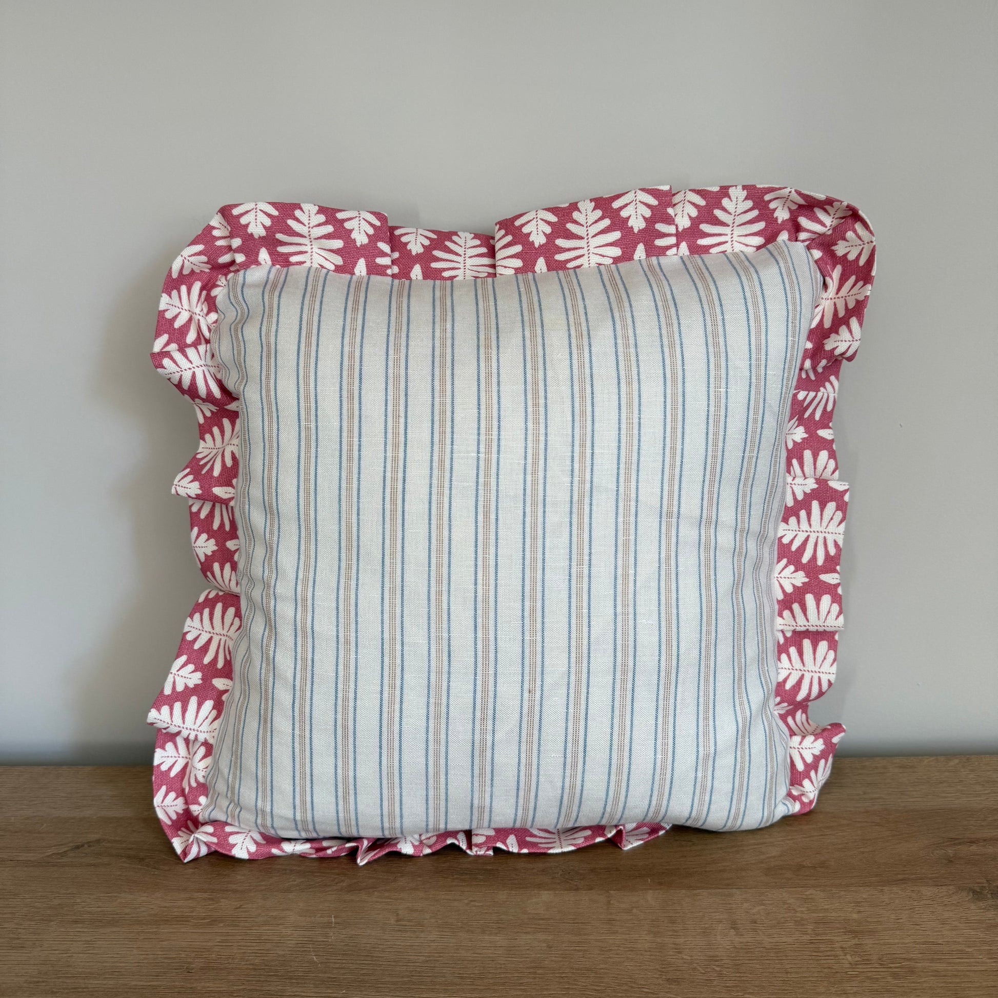 Decorative pillow with pink and white floral border on a wooden surface